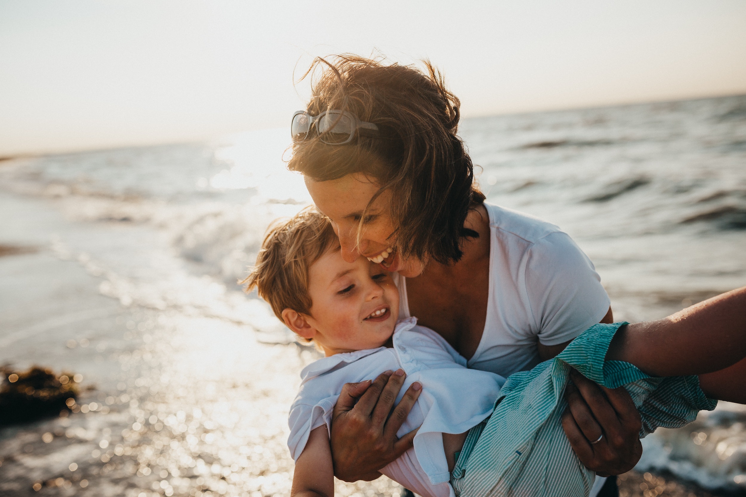 En mor holder sin søn i armene på en strand
